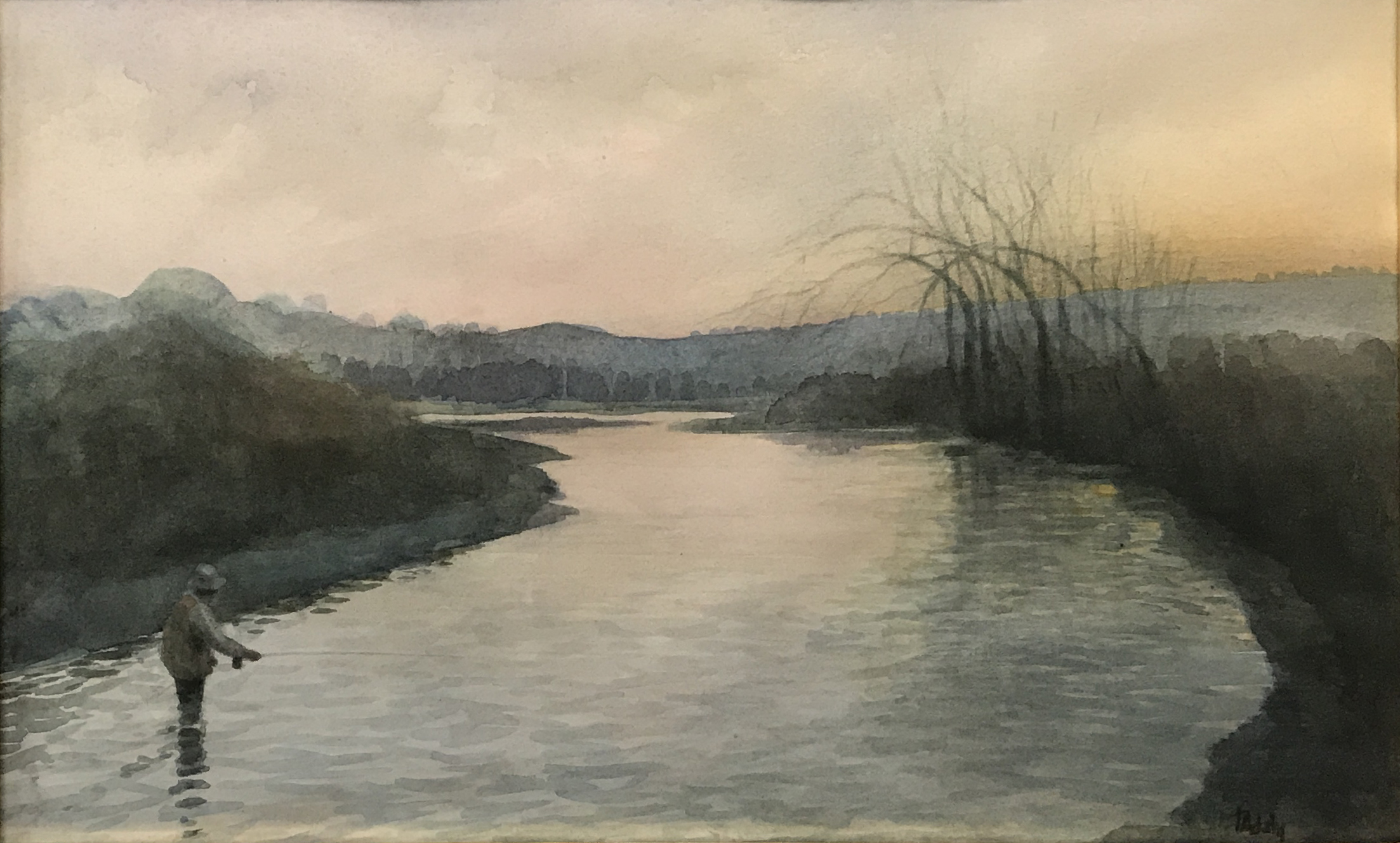 An angler stands in a stream, his rod held out low above the water.