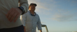 Paul Puckett stands on the deck of a boat, gazing into the distance.